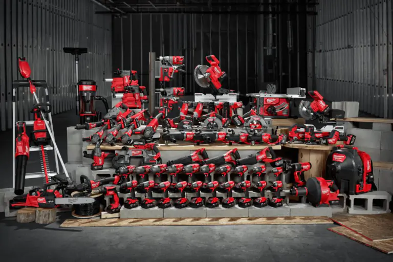 Large collection of red and black cordless power tools displayed on tiered platforms in an industrial warehouse setting