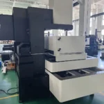 Used BQ800 CNC wire cut EDM machine with black and white enclosure positioned on a factory production floor